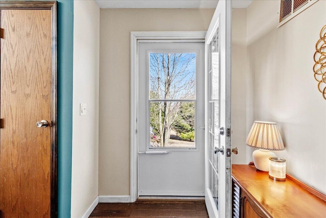 doorway to outside with visible vents, dark wood-type flooring, and baseboards