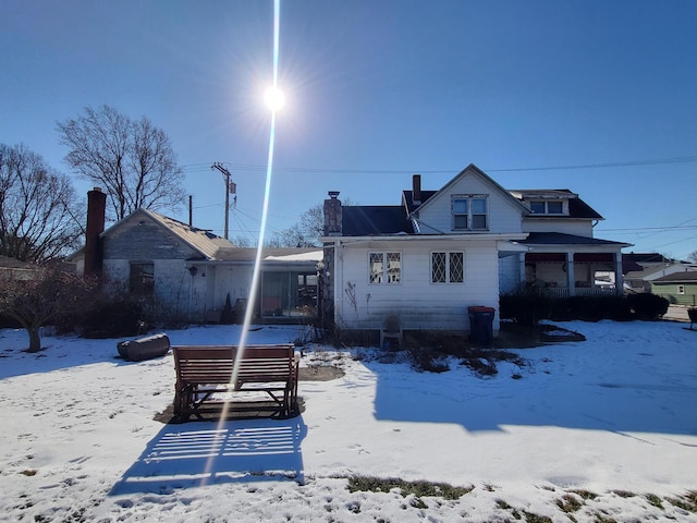 snow covered back of property featuring a hot tub