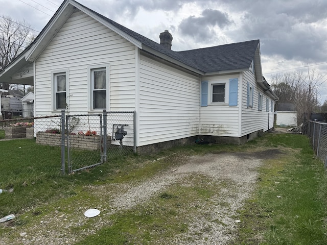 925 Sherman Ave, Springfield, OH 45503 - view of property exterior featuring a chimney, a garage, roof with shingles, a lawn, and fence private yard