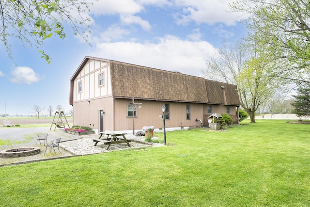 rear view of house featuring a lawn, a shingled roof, and a fire pit