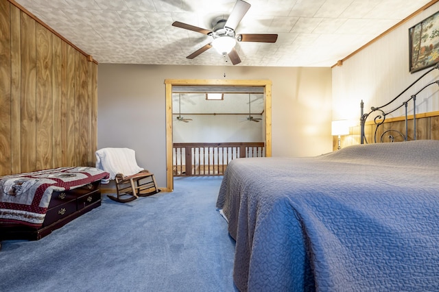 bedroom featuring access to outside, ceiling fan, wood walls, and carpet