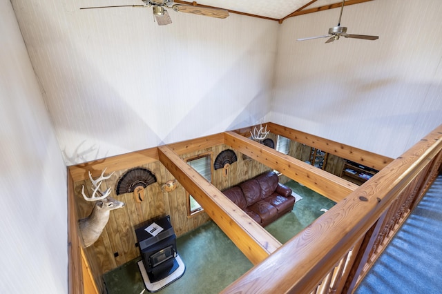 stairs with carpet flooring, a ceiling fan, wood walls, and vaulted ceiling