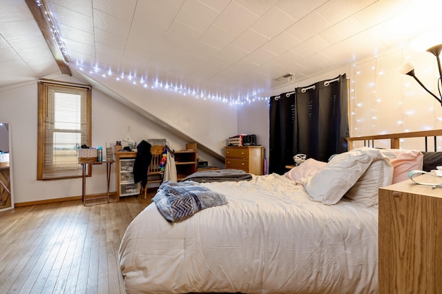 bedroom featuring baseboards, hardwood / wood-style flooring, and lofted ceiling
