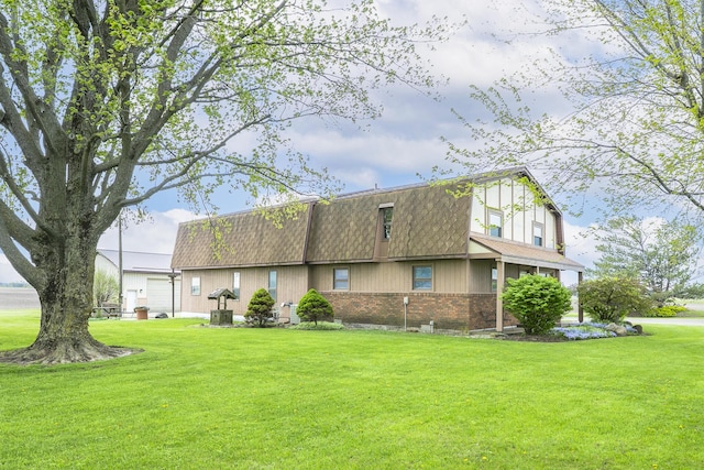 view of side of home featuring a yard, brick siding, and mansard roof