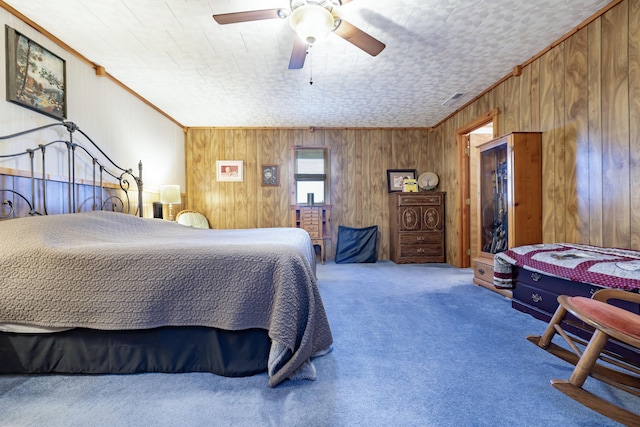 bedroom featuring wooden walls, carpet floors, crown molding, and a ceiling fan