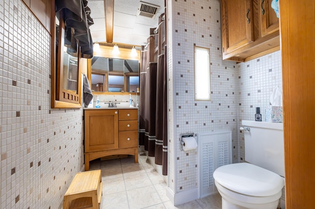 bathroom with visible vents, vanity, toilet, tile walls, and tasteful backsplash