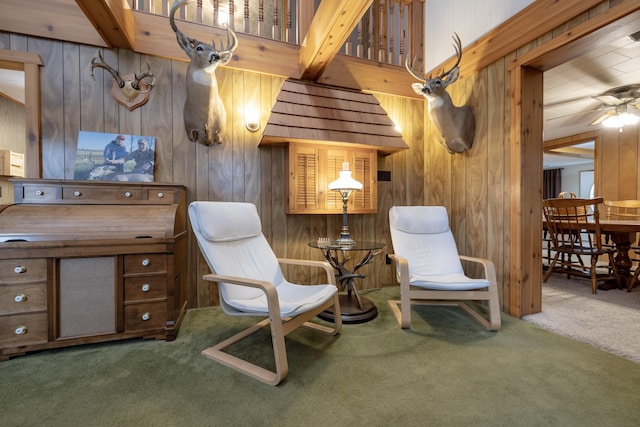 sitting room with wooden walls, carpet, and a ceiling fan