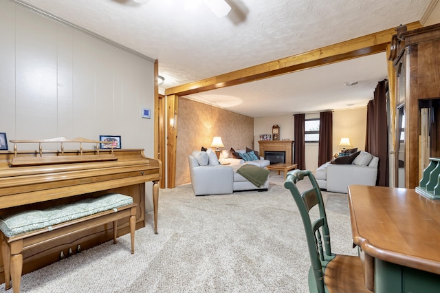 living area featuring carpet flooring, a textured ceiling, a glass covered fireplace, and beamed ceiling