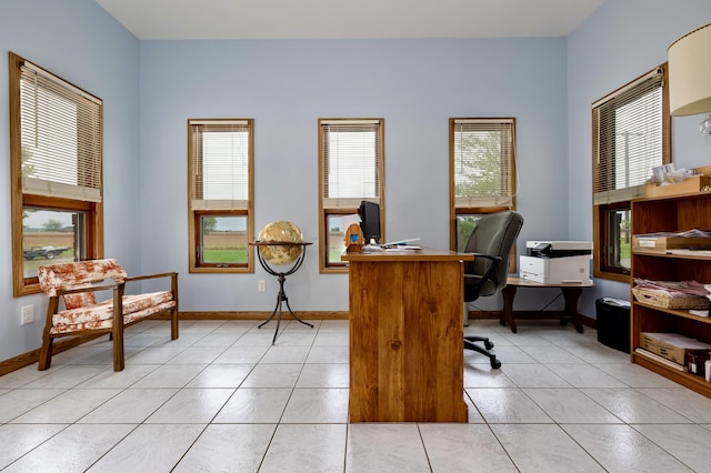 office space featuring baseboards, light tile patterned flooring, and a healthy amount of sunlight