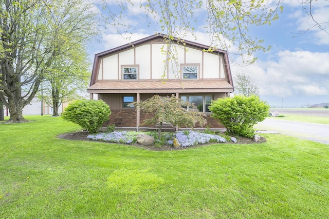 view of home's exterior featuring roof with shingles, stucco siding, a yard, and brick siding