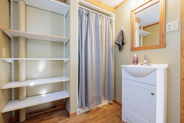 bathroom with curtained shower, wood finished floors, vanity, and baseboards