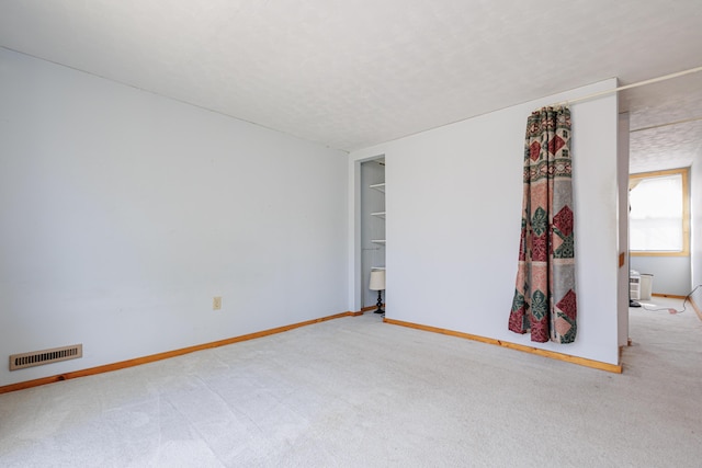 unfurnished room with baseboards, visible vents, a textured ceiling, and carpet flooring