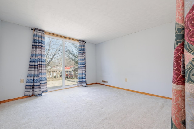 carpeted empty room featuring a textured ceiling and baseboards