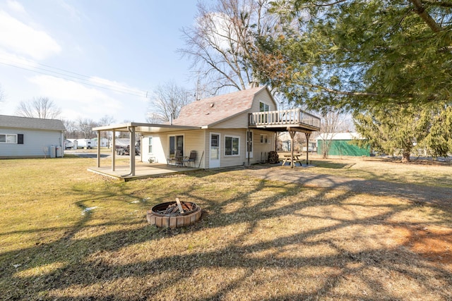 rear view of property with an outdoor fire pit, a patio area, a lawn, and a deck