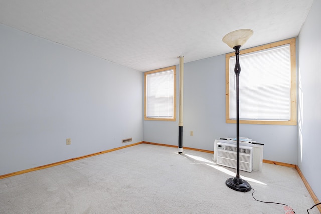 unfurnished bedroom featuring carpet, baseboards, and a wall mounted AC