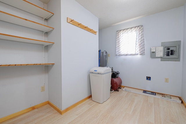 laundry area with wood finished floors, electric panel, and baseboards