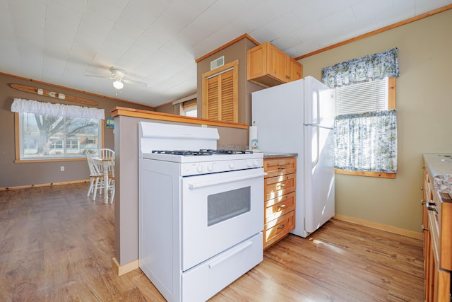 kitchen with white appliances, light wood-style flooring, visible vents, and a wealth of natural light