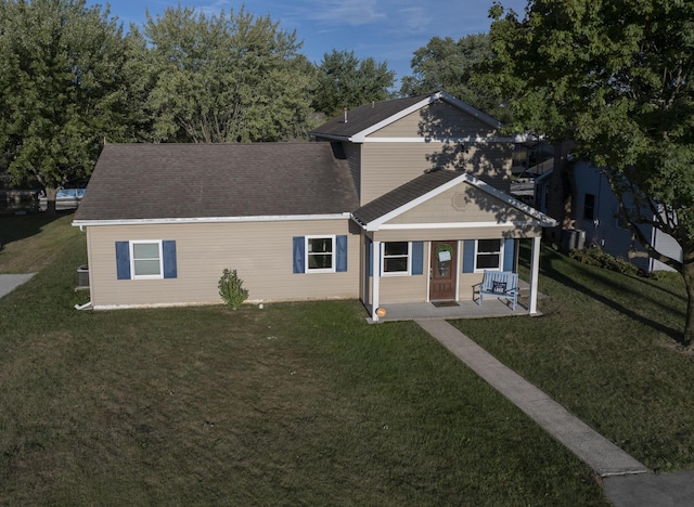 view of front facade with a shingled roof and a front yard