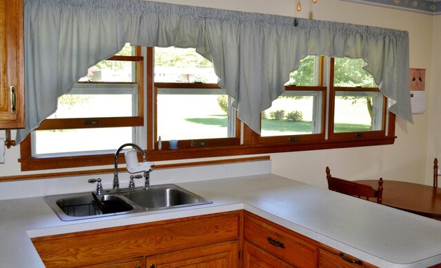 kitchen featuring brown cabinets, light countertops, and a sink