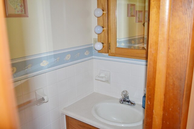 bathroom with tile walls, a wainscoted wall, and vanity