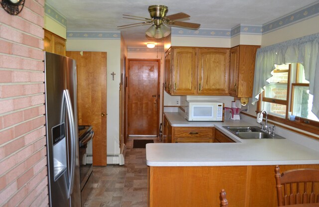 kitchen with brown cabinetry, white microwave, a peninsula, stainless steel refrigerator with ice dispenser, and a sink