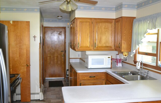 kitchen featuring light countertops, electric range, white microwave, freestanding refrigerator, and a sink