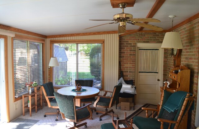 dining room featuring carpet floors, brick wall, and ceiling fan