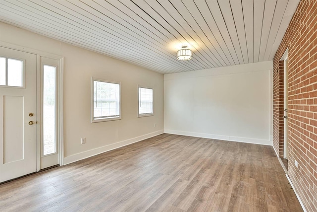 foyer entrance with baseboards, wood finished floors, wood ceiling, and brick wall