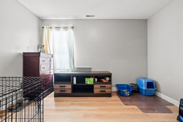 interior space with a textured ceiling, visible vents, wood finished floors, and baseboards