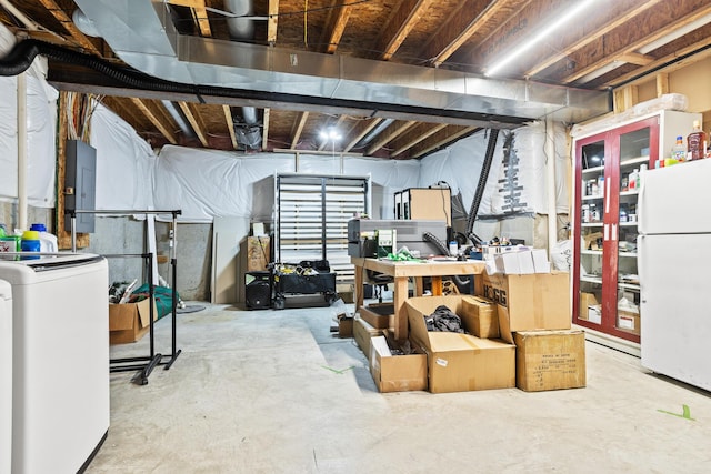 unfinished basement with electric panel, freestanding refrigerator, and washer / dryer
