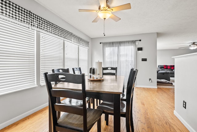 dining space with baseboards, ceiling fan, and light wood-style floors