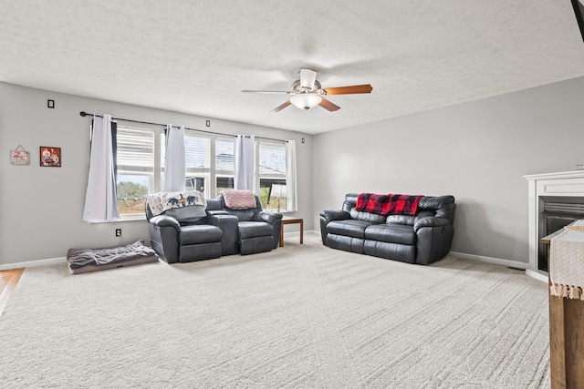 living room with baseboards, a ceiling fan, carpet floors, and a textured ceiling