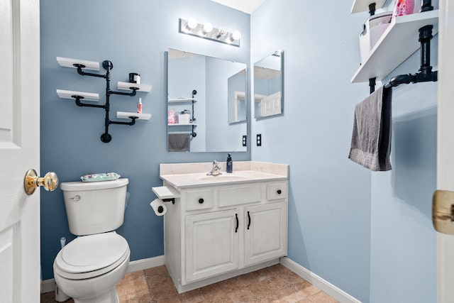 half bathroom featuring vanity, toilet, and baseboards