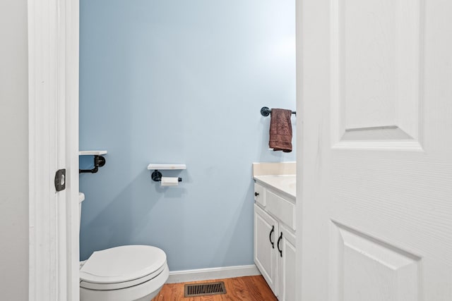 bathroom with visible vents, baseboards, toilet, wood finished floors, and vanity