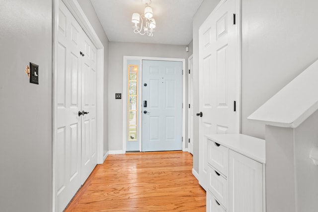 foyer with baseboards, light wood-type flooring, and a chandelier