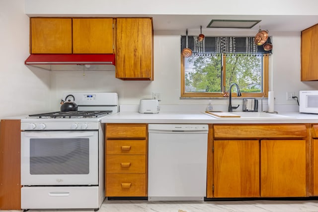 kitchen with a sink, light countertops, brown cabinets, and white appliances