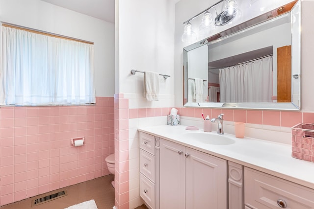 bathroom featuring visible vents, tile walls, wainscoting, vanity, and toilet