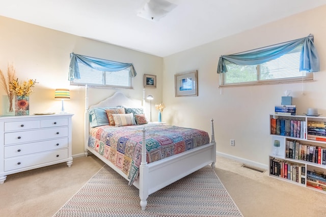 bedroom with visible vents, baseboards, multiple windows, and light carpet