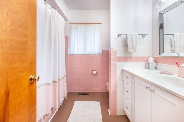 bathroom with visible vents, tile walls, a wainscoted wall, vanity, and toilet