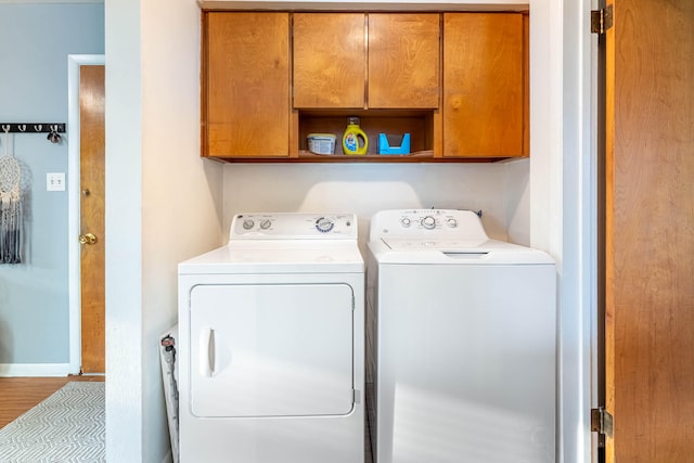 laundry room featuring cabinet space, washing machine and dryer, and wood finished floors