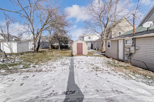 snowy yard featuring a storage shed