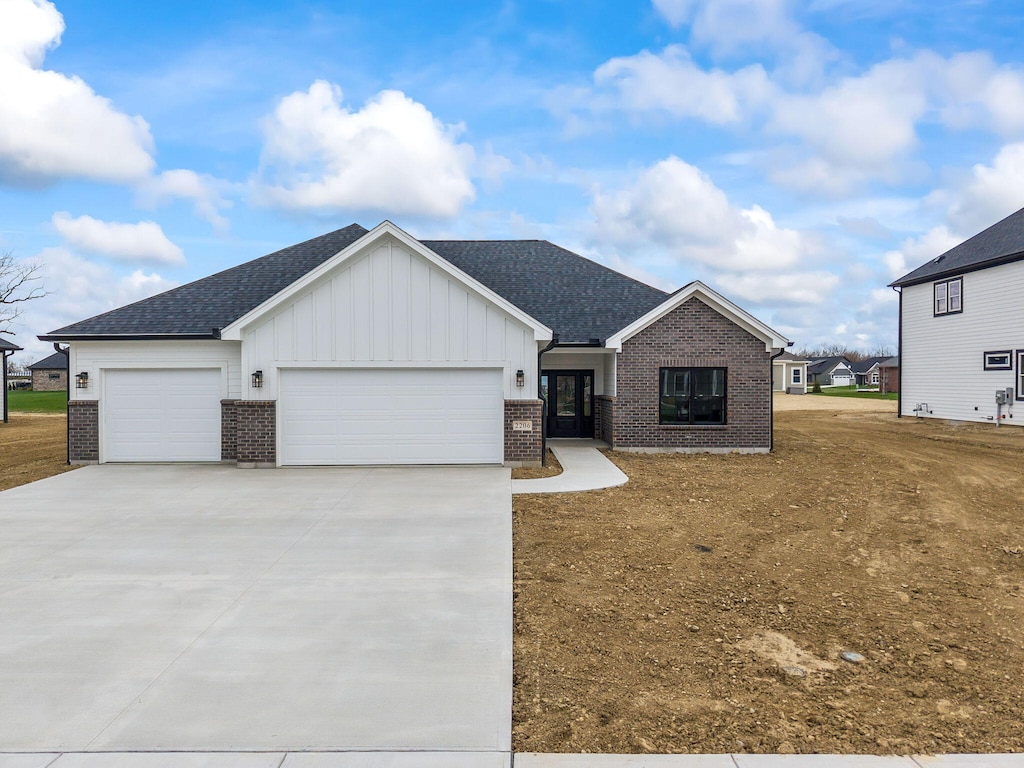 2206 Northbridge Trl, Troy, OH 45373 - view of front of home with a shingled roof, a garage, board and batten siding, brick siding, and driveway