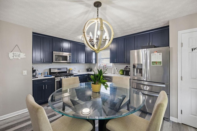 2909 W Barnhill Pl, Xenia, OH 45385 - kitchen with appliances with stainless steel finishes, a chandelier, baseboards, decorative backsplash, and wood finished floors
