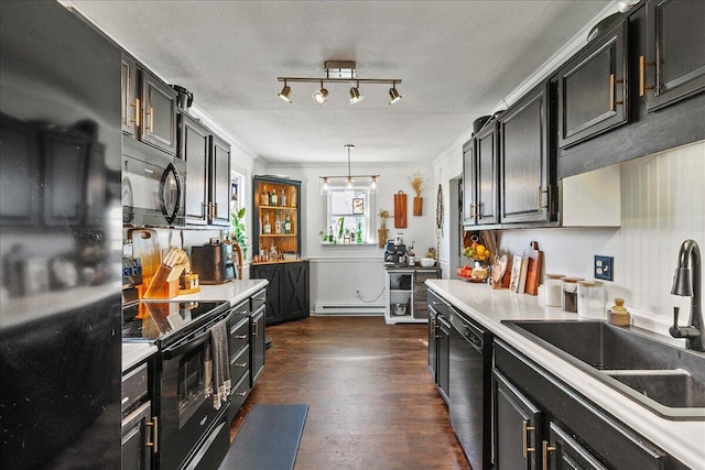 kitchen featuring dark cabinetry, dark wood-style flooring, a sink, black appliances, and light countertops