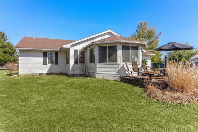 back of property with a yard, a patio area, and a sunroom