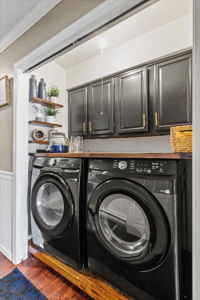 clothes washing area with ornamental molding, wainscoting, washer and dryer, dark wood-style floors, and cabinet space