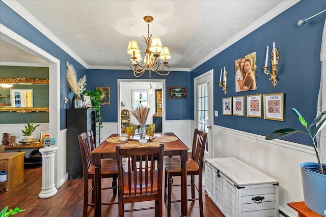 dining area with a chandelier, a wainscoted wall, ornamental molding, and dark wood-style flooring