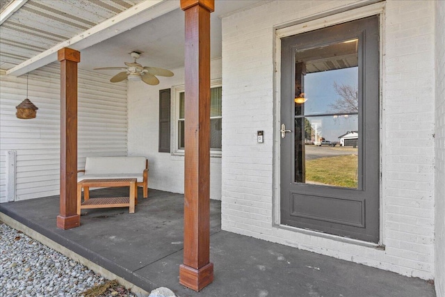 view of exterior entry featuring brick siding and ceiling fan