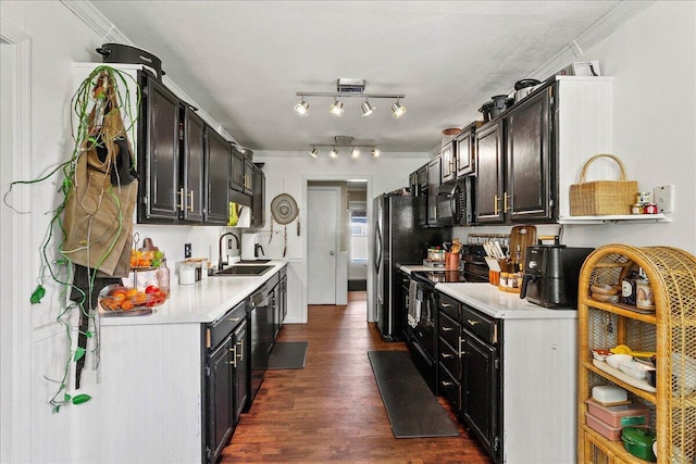 kitchen with a sink, black appliances, ornamental molding, and light countertops