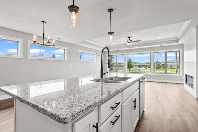1160 Waterloo St, Troy, OH 45373 - kitchen featuring a tray ceiling, light wood finished floors, an island with sink, hanging light fixtures, and white cabinets